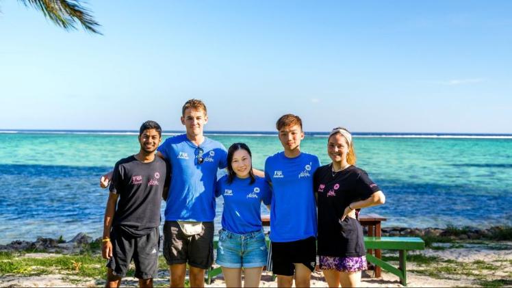 student standing together on a beach smiling